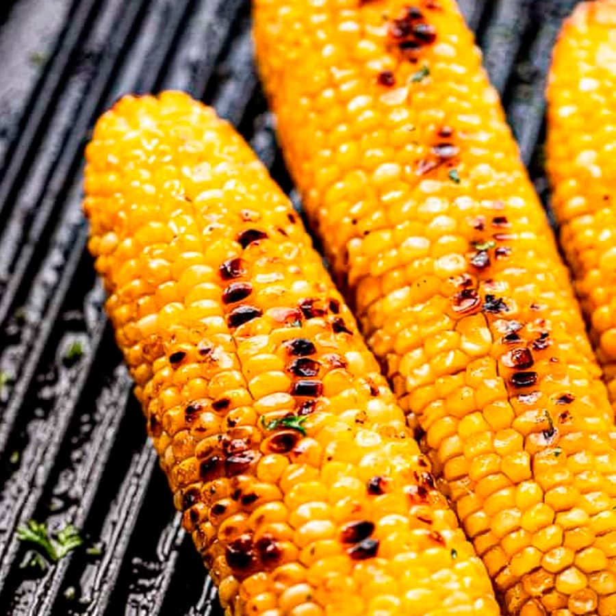 Two yellow grilled corn on the cob