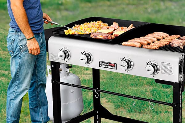man preparing meat and sausages on a propane gas grill